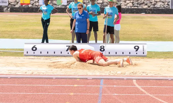 Atletizm sporcuları sahada koşuyor.