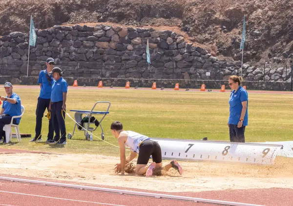 Spor giyimli genç bir kadın sahada koşuyor.