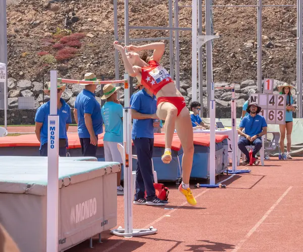 Kırmızı spor kıyafetli genç bir kız ve pistte ipi olan bir şort.