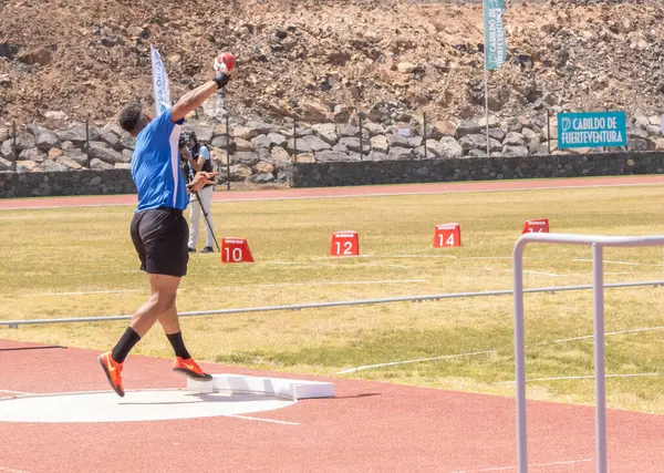 Spor giyimli genç bir erkek sporcu sahada koşuyor.