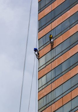 Yüksek binadaki pencereleri temizleyen bir grup işçi