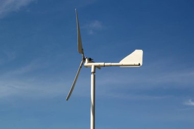 Açık mavi gökyüzündeki küçük bir yel değirmeninin yakınında