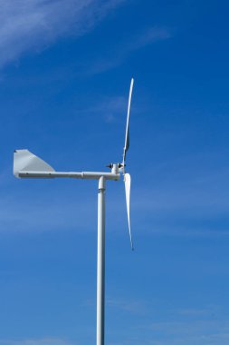 Açık mavi gökyüzündeki küçük bir yel değirmeninin yakınında