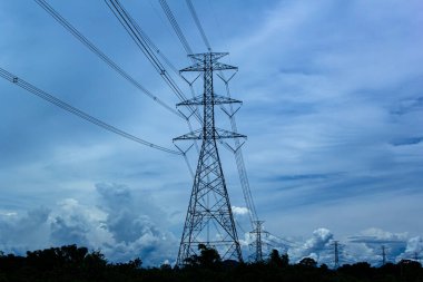 Mavi gökyüzüne karşı elektrik iletim pilonu silueti