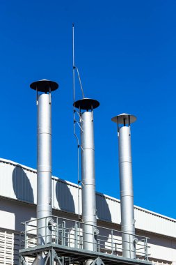 Kazan dairesinin boruları mavi gökyüzüne karşı. Soyut sanayi geçmişi.