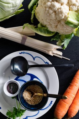 Sağlıklı Asya yemekleri, sağlıklı gıda konsepti. Taze sebze, karnabahar, hoisin sosu, havuç ve ahşap tabakta kara biber. 