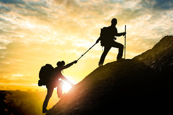 Два туриста с рюкзаками взбираются на красивый закат в Таиланде в небе.