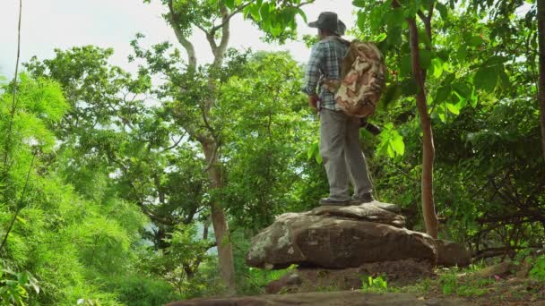 男性の観光客バックパッカーは 岩の上に座って写真を撮ります 休暇旅行 山の森の景色ポイント タイで最高の国立公園でのソロアドベンチャー旅行 — ストック動画