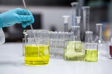 Bilim adamı laboratuardaki kozmetik ürününün formülasyon testi için bir deney şişesinde emülsifikatör çözeltisi hazırlıyor. Araştırma ve Geliştirme Kozmetikleri.