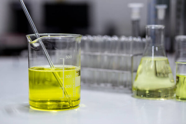 Pale yellow solution of an emulsifier a beaker for formulation test of the cosmetic product in the laboratory or industry. Research and Development of cosmetics