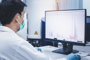 Scientist man checks the spectrum of sample analysis by nuclear magnetic resonance spectroscopy, NMR spectroscopy, as shown on a computer monitor in the laboratory. clipart