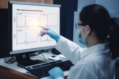 Bilim kadını, laboratuardaki kütle spektrometre cihazının bilgisayar monitöründe gösterildiği gibi kütle spektrometri analizinin sonuçlarının kromatogramını gösteriyor..