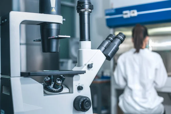 Inverterat Mikroskop Och Suddig Kvinnlig Forskare Som Arbetar Laboratoriets Dragskåp — Stockfoto