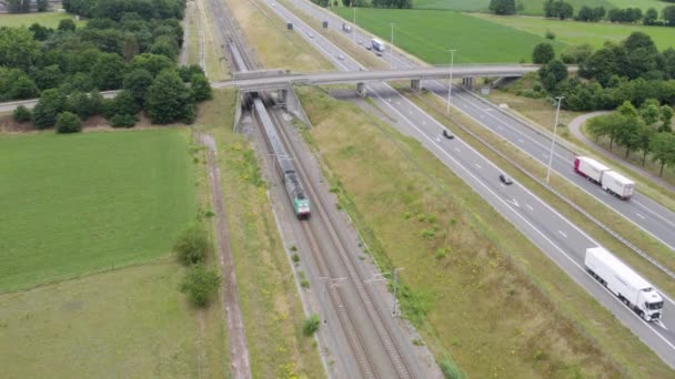 与公路相邻的农村铁路 通过桥梁 火车和汽车 空中景观 美丽的绿色风景 自然和交通概念 高质量4K — 图库视频影像
