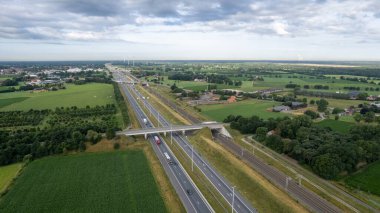 Brecht, Belgium, 6th of July, 2022, Panoramic aerial drone view of wind farm or wind park, with high wind turbines for generation electricity with the motorway with few cars and railroad next to it