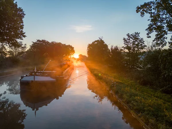 Stock image Aerial view of a colourful dramatic sunrise sky over a canal with a cargo boat in Belgium. Canals with water for transport, agriculture. Fields and meadows. Landscape aerial view shot from a drone