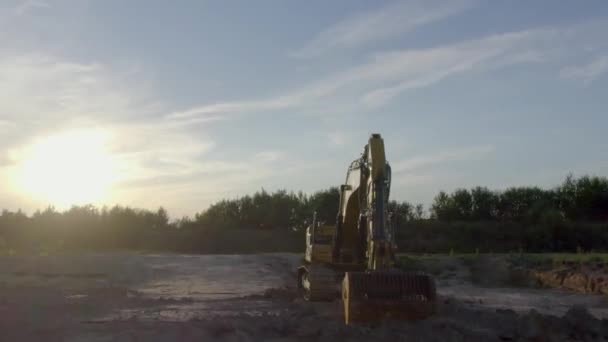 地球の移動装置 黄色い掘削機が地面を掘ってる 掘削機のバケツは 無人機が上昇して撮影された 自然の日没の背景に土壌をすくい取ります 高品質4K映像 — ストック動画