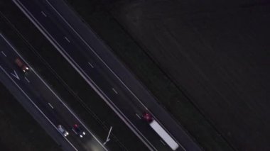 Hava kararınca insansız hava aracı iki şeritli bir otoyolda giderken küçük bir yol üzerinde uçuyor. Arabalar, tarlalar ve ağaçlar karanlık, kasvetli bir yol görüntüsü. Gece şehir dışında karanlık bir kırsal yolda araba sürüyor.