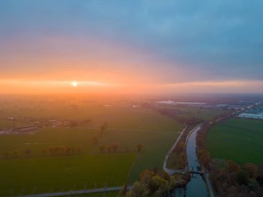 Sonsuz yemyeşil otlakların ve Belçika 'nın dramatik renkli günbatımı gökyüzünün altındaki tarım arazilerinin havadan görünüşü. Zümrüt yeşili tarlaları ve çayırları olan güzel bir Antwerp kırsalı. Gün batımında kırsal alan. Yüksek