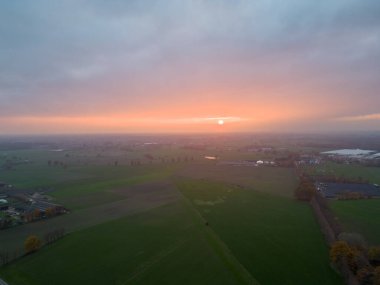 Sonsuz yemyeşil otlakların ve Belçika 'nın dramatik renkli günbatımı gökyüzünün altındaki tarım arazilerinin havadan görünüşü. Zümrüt yeşili tarlaları ve çayırları olan güzel bir Antwerp kırsalı. Gün batımında kırsal alan. Yüksek
