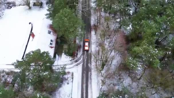 冬には雪氷の道をドライブする無人偵察機からの空中トップビュー 農場や森林に囲まれた地域に移動する自動車の鳥の目のビュー — ストック動画