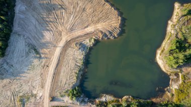 Aerial drone photo of Quarry turquoise green lake colour and the pathways of the equipment and excavators, open pit clay mining in Belgium. High quality photo