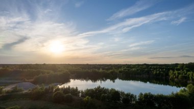 Aerial panoramic landscape over a winding forest road in Belgium, during sunset, drone shot. High quality photo