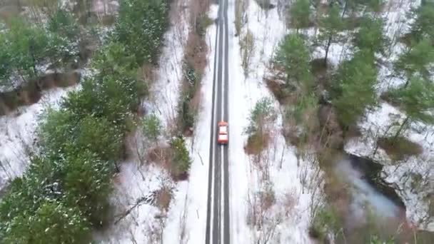冬季在雪地冰道上驾驶的橙色越野车俯瞰当地风景 鸟瞰汽车在农田和森林环绕地区行驶的景象 — 图库视频影像