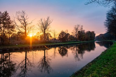 Yeşil çalıları ve renkli gökyüzü olan bir nehrin üzerinde güzel bir günbatımı. Yüksek kalite fotoğraf