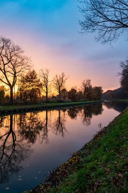 Yeşil çalıları ve renkli gökyüzü olan bir nehrin üzerinde güzel bir günbatımı. Yüksek kalite fotoğraf