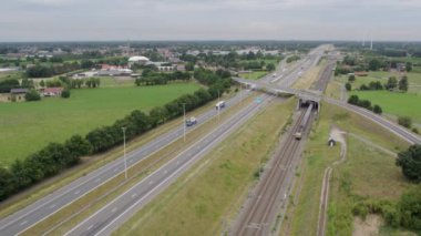 Otobanın yanındaki kırsal alanda demiryolu, geçen arabalar, hava manzarası - güzel yeşil manzara, seyahat, doğa ve ulaşım kavramları. Yüksek kalite 4k görüntü
