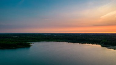 Göl kıyısında dramatik ve renkli bir gün batımının insansız hava aracı tarafından çekilen hava görüntüsü. Doğa manzarası. Avrupa 'da doğa. Yansıma, mavi gökyüzü ve sarı güneş ışığı. Gün doğumunda manzara veya
