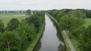 Rijkevorsel, kempen, Belçika 'daki bir İHA' nın Dessel Schoten kanalı üzerinde çektiği renkli ve dramatik günbatımı doğal yeşil tarım arazisindeki su yolunu gösteriyor. Yükseğe. Yüksek