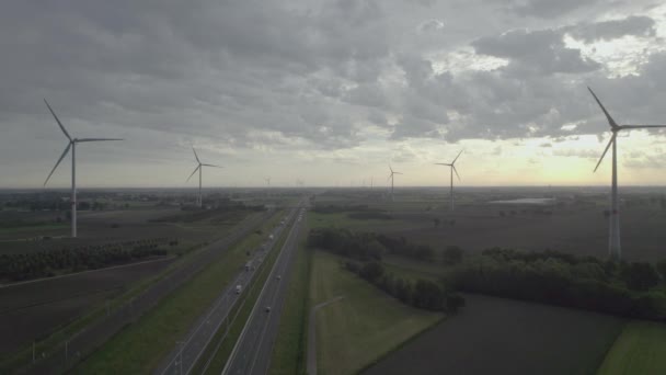 ドローンから高速道路や鉄道沿いの風車農場でのパノラマの空中ビュー 大規模な風力タービンのシネマティックな空中ビューは クリーンな持続可能なエネルギー クリーンエネルギーの未来を生成します 風車の農場 — ストック動画
