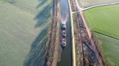 Güneşli bir kış gününde bir kargo kanalı gemisinin hava görüntüsü kanaldan geçer, suda yansımalar görülür, Belçika, Rijkevorsel 'in eteklerindeki kanal sistemi. Yüksek