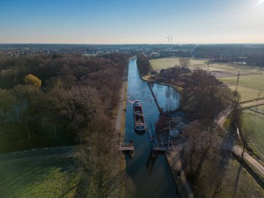Belçika 'da bir kargo teknesiyle bir kanalın üzerinde renkli dramatik bir gündoğumu manzarası. Ulaşım ve tarım için suyu olan kanallar. Tarlalar ve çayırlar. Bir İHA 'dan manzara görüntüsü