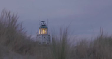 Hollanda, Ouddorp 'taki Vuurtoren Westhoofd Deniz Feneri' nin Kırmızı Tuğla Yapısı. Önünde kum tepeleri ve kum tepecikleri olan dar bir çekim. Yüksek kalite 4k görüntü