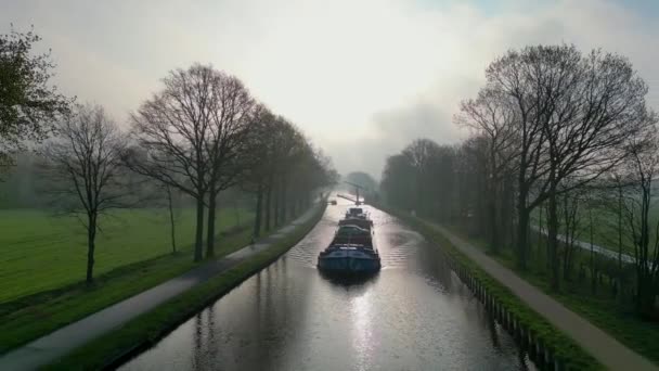 貨物運河船の無人機からの空中ビューは晴れた冬の日に運河を通過し 反射はベルギーのRijkevorsel郊外の水 運河システムで見られることになっています — ストック動画