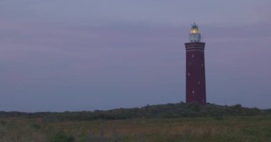 Hollanda, Ouddorp 'taki Vuurtoren Westhoofd Deniz Feneri' nin Kırmızı Tuğla Yapısı. Önünde kum tepeleri ve kum tepecikleri olan dar bir çekim. Yüksek kalite 4k görüntü