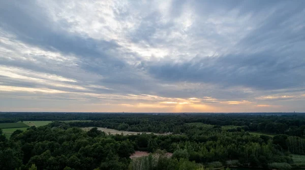 Aerial view dramatic storm sky landscape with sun rays between the clouds and over the forests. Dark moody cloudscape. High quality photo