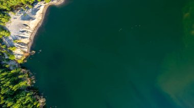 Blue lakes from above. Lakes in green forest in evening sunlight aerial drone view. Scenic summer background. Picturesque lakeside with forest. High quality photo. High quality photo