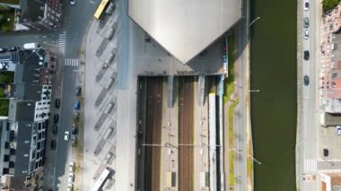 Belçika 'da bir kanal ve tren istasyonunun havadan görüntüsü. Trenler beklerken bir feribot ve kargo gemisi geçiyor. Yüksek kalite 4k görüntü
