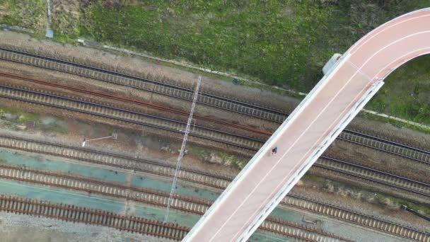 線路の上を自転車や歩道橋の下を通過する列車の無人機によって撮影された空中ビュー 高品質4K映像 — ストック動画