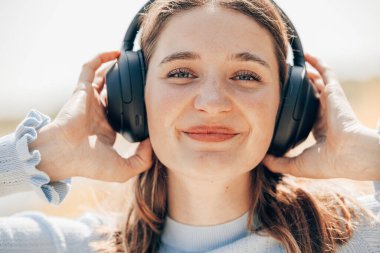 Doğada kablosuz kulaklıkla müzik dinleyen güzel genç bir kadının yüzü. Kulağında kablosuz kulaklık olan bir kadın. Yüksek kalite fotoğraf