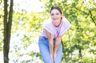 Ormanda güneş ışığında genç ve güzel bir esmer kızın portresi. Neşeli bir gülümseme ile gülüyor. Duyguları rahatlatan bir mutluluk. Yüksek kalite fotoğraf