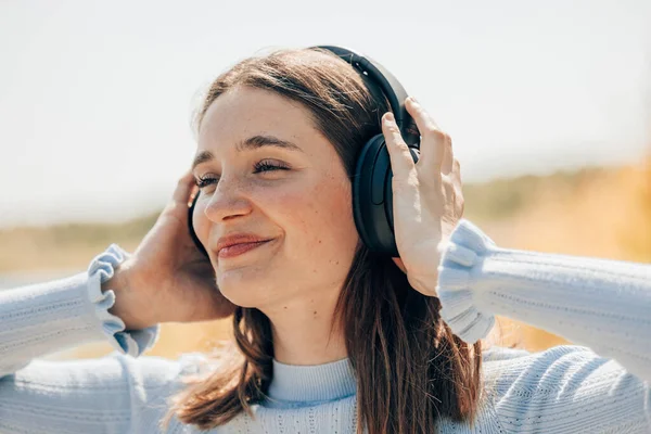 一个漂亮的年轻女子的脸 她正在外面用无线耳机听音乐 耳朵上戴着无线耳机的女人高质量的照片 — 图库照片