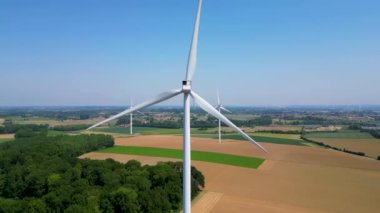 Enerji üretimi için tarım arazisindeki güzel bulutsuz mavi gökyüzünde güçlü rüzgar türbini çiftliğinin havadan yakın görüntüsü. Rüzgar güç türbinleri sürdürülebilir enerji üretmek için temiz yenilenebilir enerji üretir