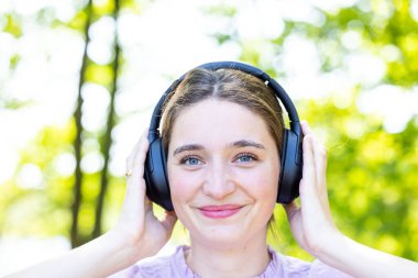 Melodik Bliss: Müzikal Zevkte Kaybolan Güzel Esmer 'in Yakın Çekim Portresi, kulaklıkla müzik dinleyen ve keyifle gülümseyen güzel bir esmerin portresi. Yüksek