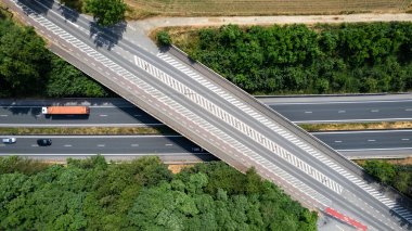 Bu çarpıcı hava görüntüsü, Belçika 'nın güneşli bir yaz gününde düzenli bir otobanının güzelliğini yansıtıyor. Yol, etkileyici köprüsü ile, geniş verimli orman ve tarlalar boyunca uzanır.