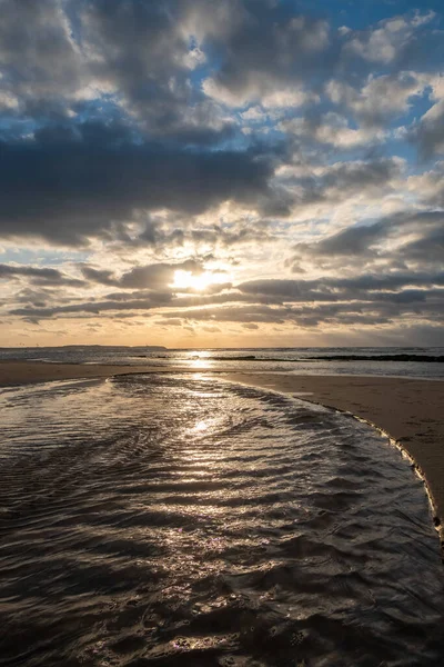 Великолепный Снимок Впечатляющего Закатного Неба Отражающегося Песчаном Пляже Ритмичных Волнах — стоковое фото